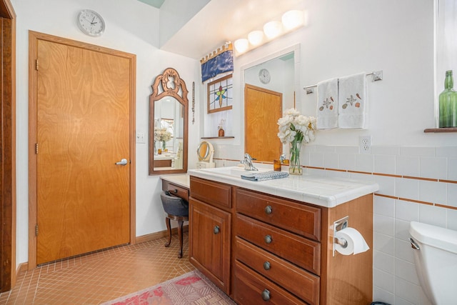 bathroom with toilet, tile walls, tile patterned flooring, and vanity