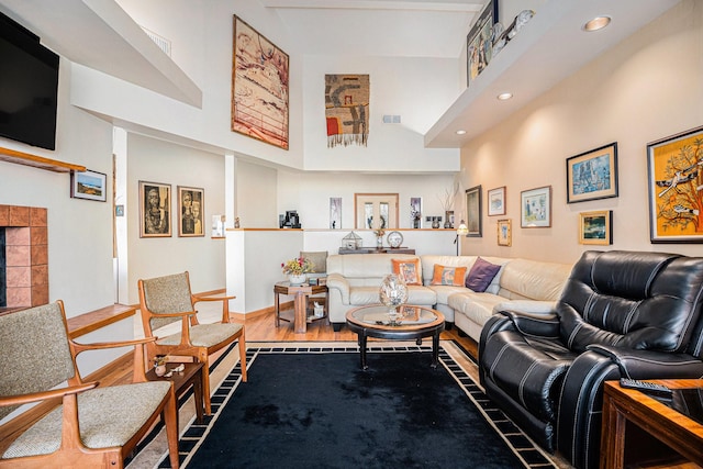 living room featuring a tile fireplace, a high ceiling, and hardwood / wood-style flooring