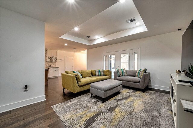 living room with a raised ceiling, french doors, and dark wood-type flooring