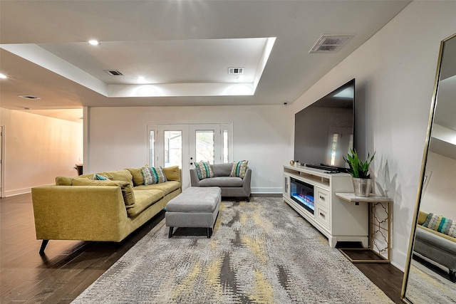 living room with a tray ceiling, dark hardwood / wood-style floors, and french doors