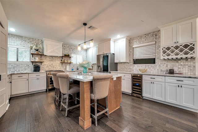 kitchen with white cabinetry, stainless steel appliances, decorative light fixtures, wine cooler, and a center island