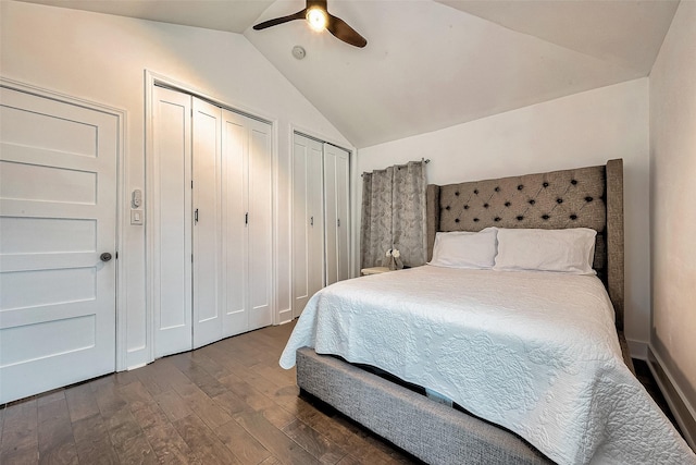 bedroom with ceiling fan, dark hardwood / wood-style flooring, lofted ceiling, and two closets