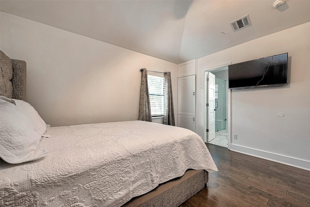 bedroom featuring lofted ceiling, dark wood-type flooring, and connected bathroom