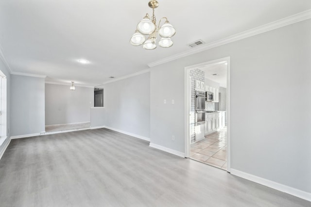 spare room with light wood-type flooring, an inviting chandelier, and ornamental molding