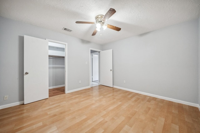 unfurnished bedroom featuring light wood-type flooring, ceiling fan, a textured ceiling, and a closet