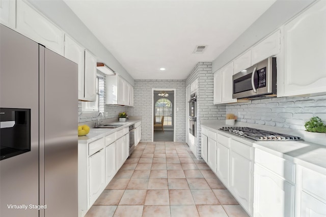 kitchen with white cabinetry, stainless steel appliances, decorative backsplash, sink, and light tile patterned floors