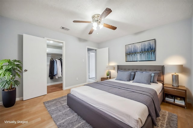 bedroom featuring light wood-type flooring, a closet, a textured ceiling, and ceiling fan