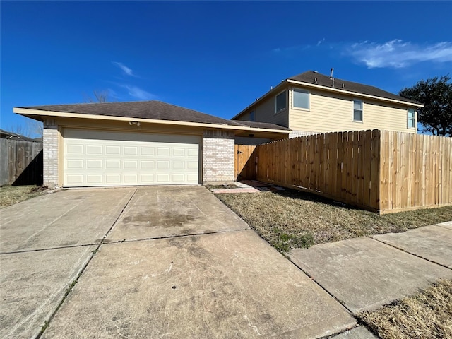 view of front of house featuring an outbuilding, brick siding, an attached garage, fence, and driveway