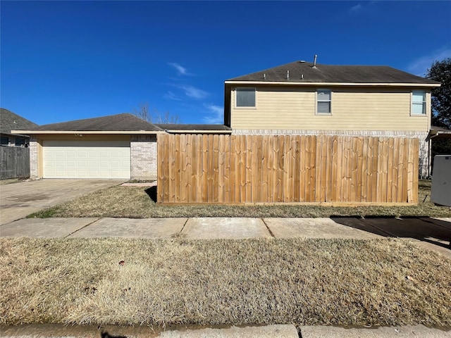 view of property exterior with a garage, brick siding, and fence