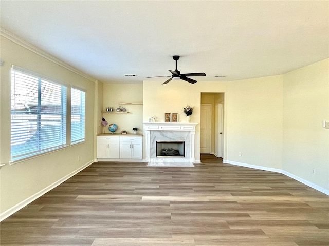 unfurnished living room with ceiling fan, a high end fireplace, and light hardwood / wood-style floors