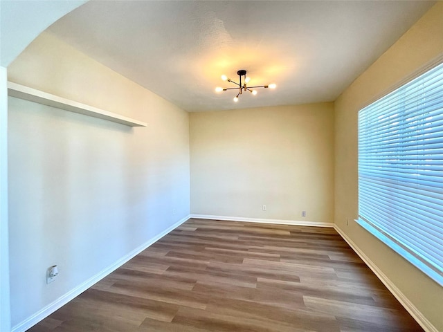 unfurnished room with baseboards, a chandelier, and wood finished floors