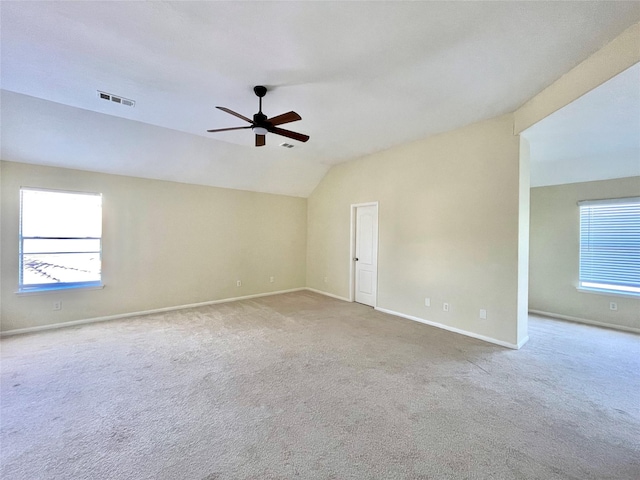 carpeted spare room with a wealth of natural light, visible vents, vaulted ceiling, and baseboards