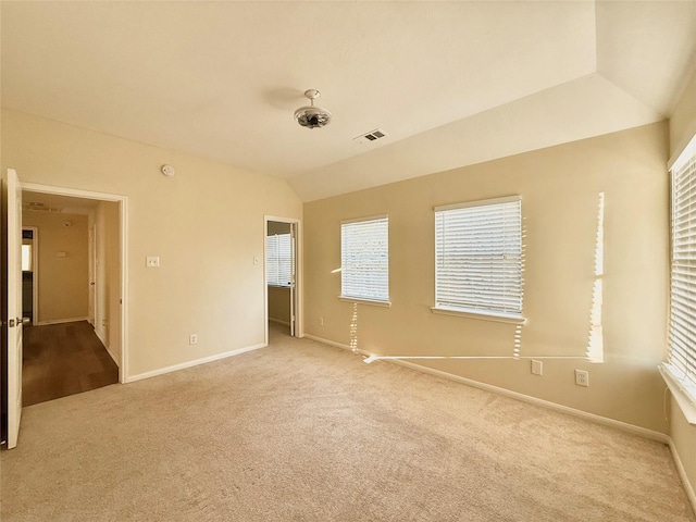 empty room featuring carpet, visible vents, vaulted ceiling, and baseboards