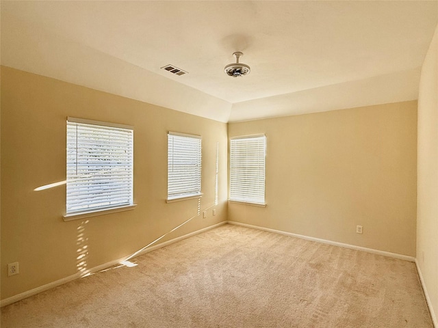 unfurnished room with baseboards, lofted ceiling, visible vents, and light colored carpet