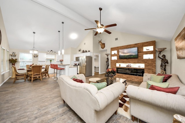 living room with ceiling fan with notable chandelier, wood-type flooring, and high vaulted ceiling