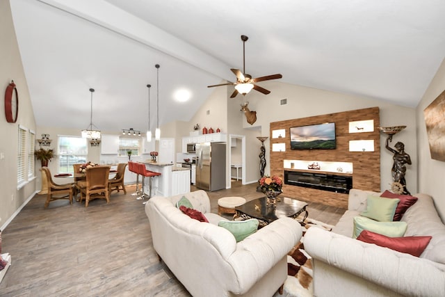 living room with ceiling fan, light wood-type flooring, and vaulted ceiling with beams