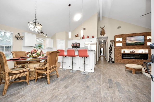 kitchen with pendant lighting, a breakfast bar, white cabinetry, stainless steel appliances, and a chandelier