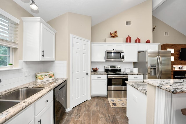 kitchen featuring lofted ceiling, tasteful backsplash, sink, white cabinetry, and stainless steel appliances