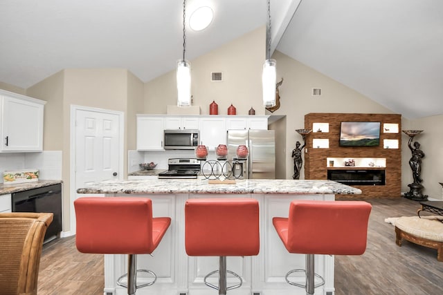 kitchen with tasteful backsplash, white cabinets, hanging light fixtures, and stainless steel appliances