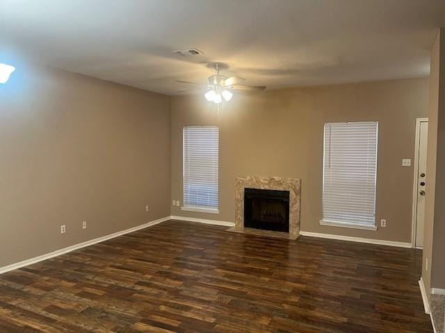 unfurnished living room featuring ceiling fan, dark wood-type flooring, and a high end fireplace