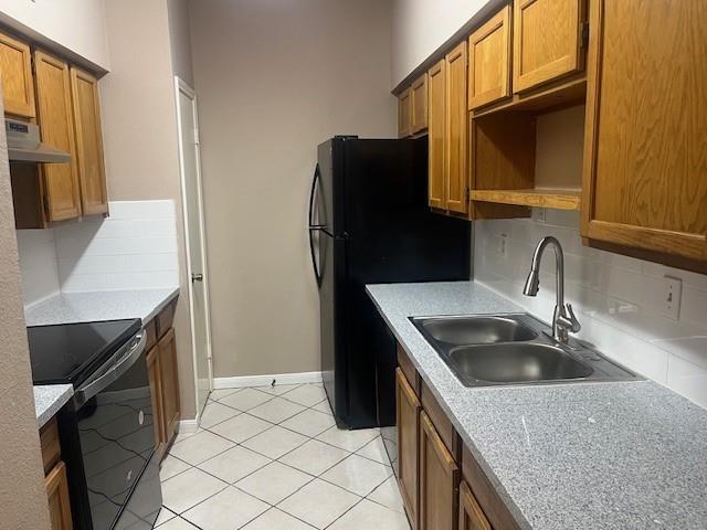 kitchen featuring electric stove, backsplash, sink, black refrigerator, and light tile patterned floors