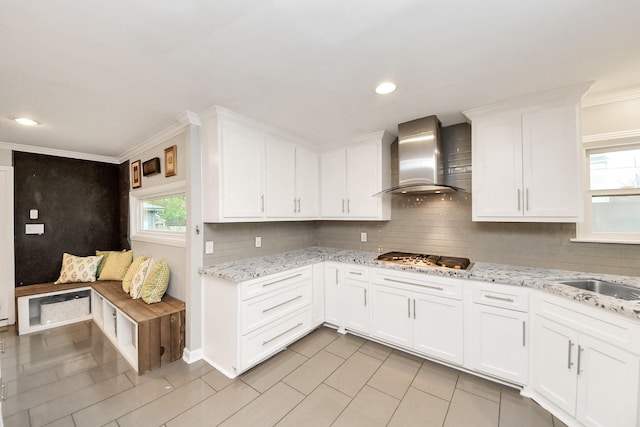 kitchen featuring white cabinetry, wall chimney range hood, stainless steel gas stovetop, and a healthy amount of sunlight