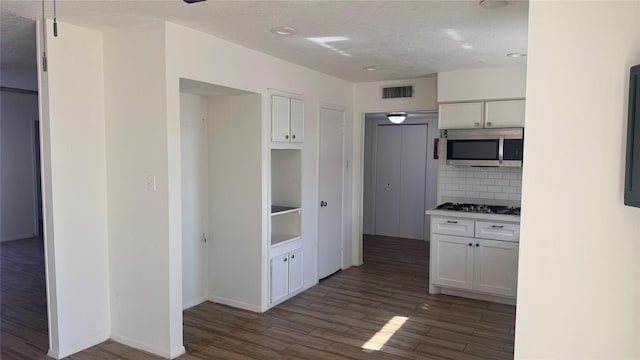 kitchen with white cabinets, stainless steel appliances, dark hardwood / wood-style flooring, and tasteful backsplash