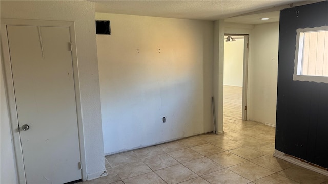 spare room with a textured ceiling and light tile patterned flooring