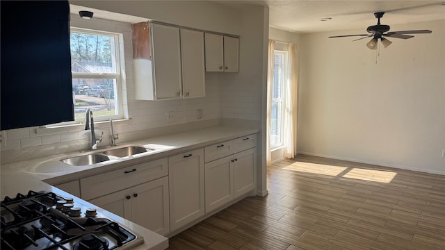 kitchen with sink, gas stovetop, white cabinets, and decorative backsplash