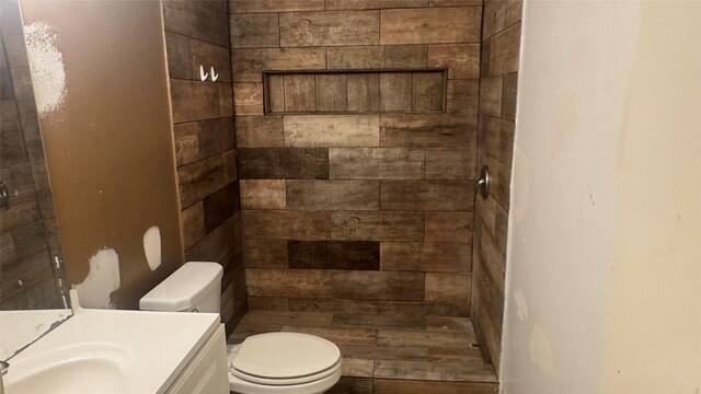 bathroom with vanity, toilet, and a tile shower