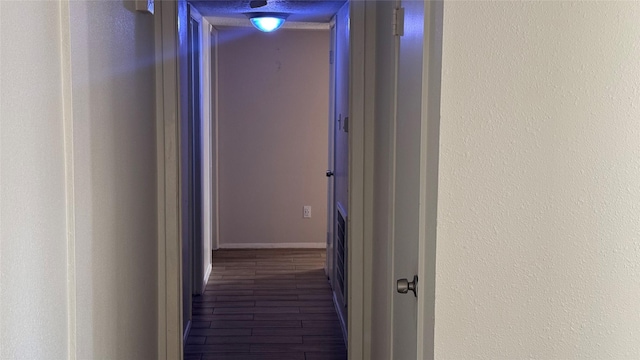 corridor with a textured ceiling and wood-type flooring