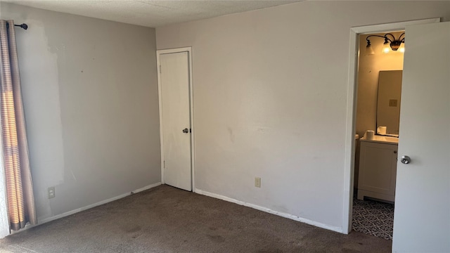 unfurnished bedroom featuring connected bathroom and dark carpet