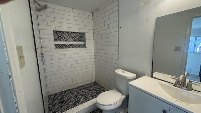 bathroom with vanity, toilet, and tiled shower