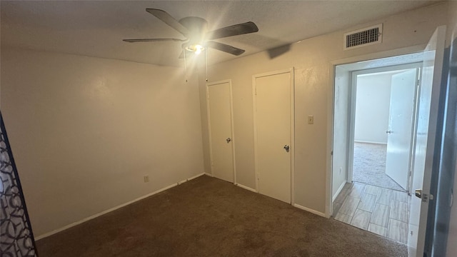 unfurnished bedroom with ceiling fan and dark colored carpet