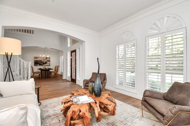 living room featuring hardwood / wood-style floors, crown molding, and a chandelier