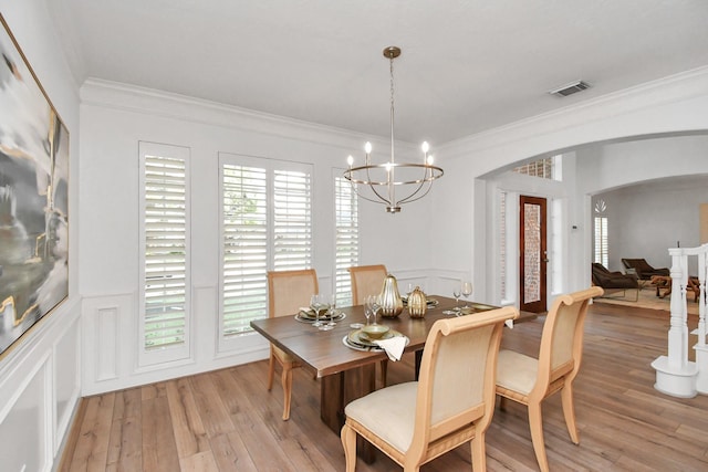 dining space with crown molding, light hardwood / wood-style floors, and a notable chandelier