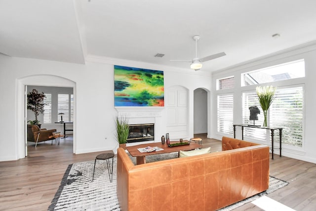 living room with ceiling fan, crown molding, and light hardwood / wood-style floors