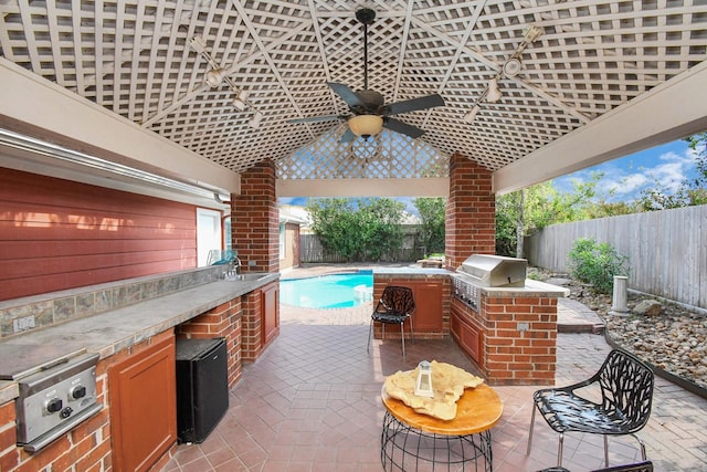 view of patio with a fenced in pool, a grill, and exterior kitchen