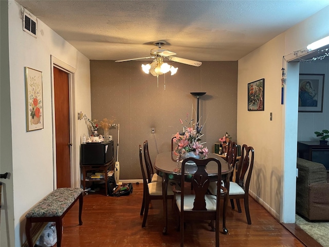 dining room with ceiling fan, dark wood-type flooring, and a textured ceiling