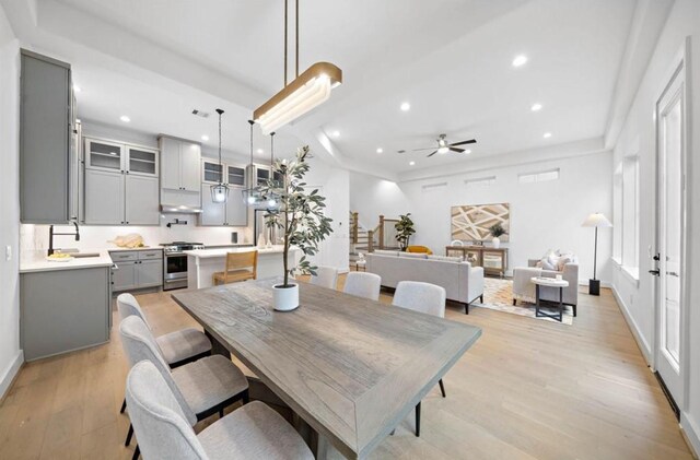 dining space with ceiling fan, sink, and light hardwood / wood-style flooring