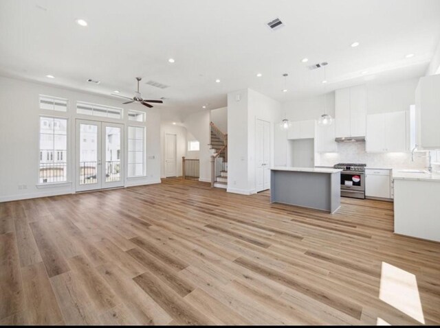 unfurnished living room featuring french doors, ceiling fan, light hardwood / wood-style flooring, and sink