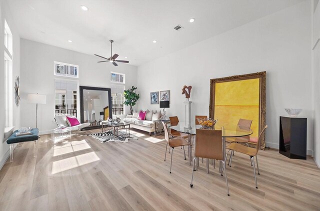 dining area featuring ceiling fan, a towering ceiling, and light hardwood / wood-style flooring