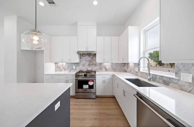 kitchen featuring pendant lighting, white cabinets, appliances with stainless steel finishes, tasteful backsplash, and sink