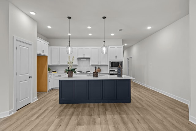 kitchen featuring pendant lighting, built in microwave, white cabinetry, backsplash, and a kitchen island with sink