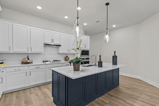 kitchen with white cabinetry, a kitchen island with sink, stainless steel appliances, tasteful backsplash, and decorative light fixtures