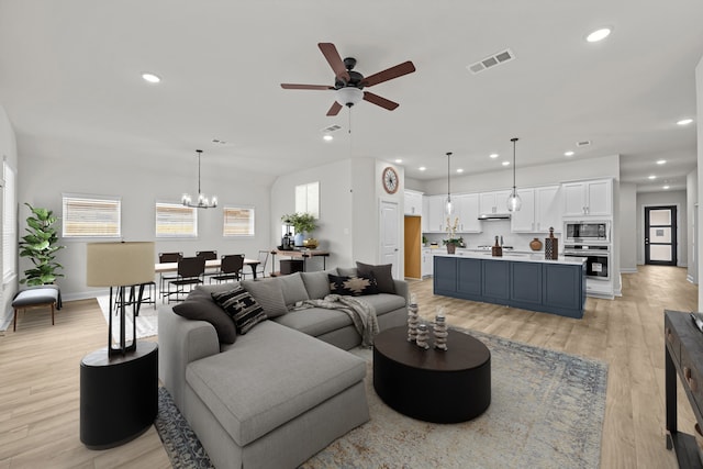 living room featuring ceiling fan with notable chandelier and light hardwood / wood-style floors