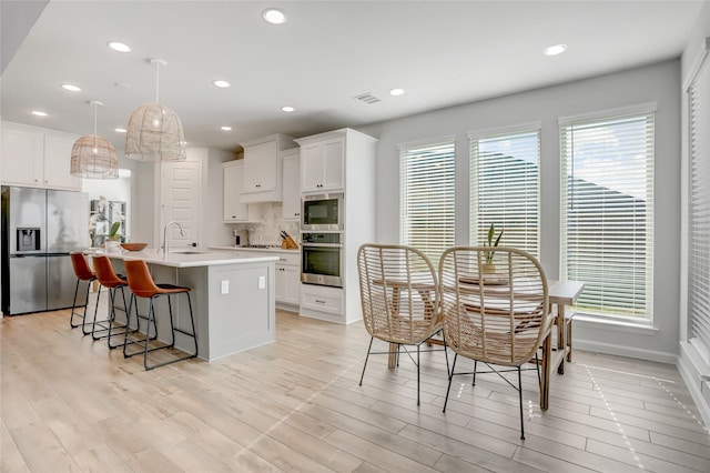 kitchen with plenty of natural light, white cabinetry, appliances with stainless steel finishes, and a kitchen island with sink