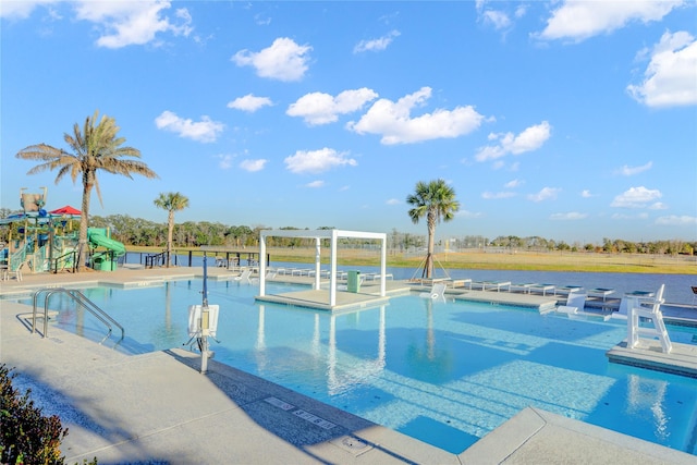 view of pool with a water slide, a patio, and a playground