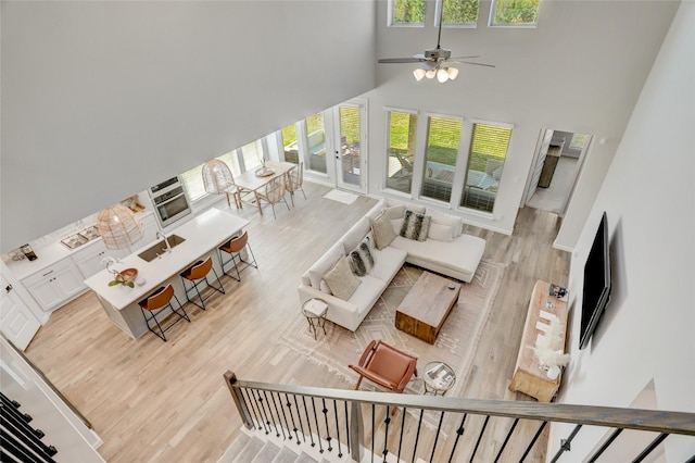 living room featuring hardwood / wood-style flooring, ceiling fan, a healthy amount of sunlight, and a high ceiling