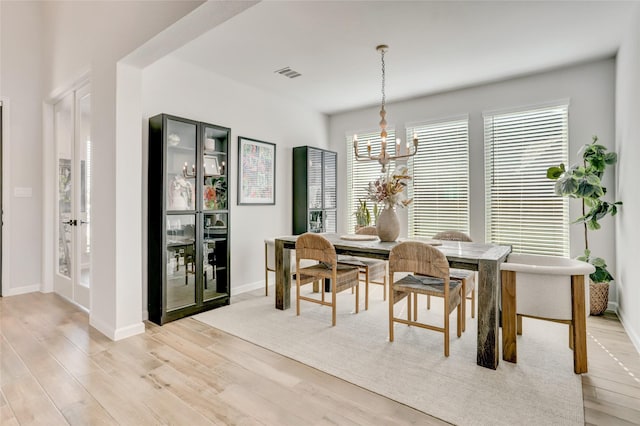 dining space featuring light hardwood / wood-style flooring and a notable chandelier